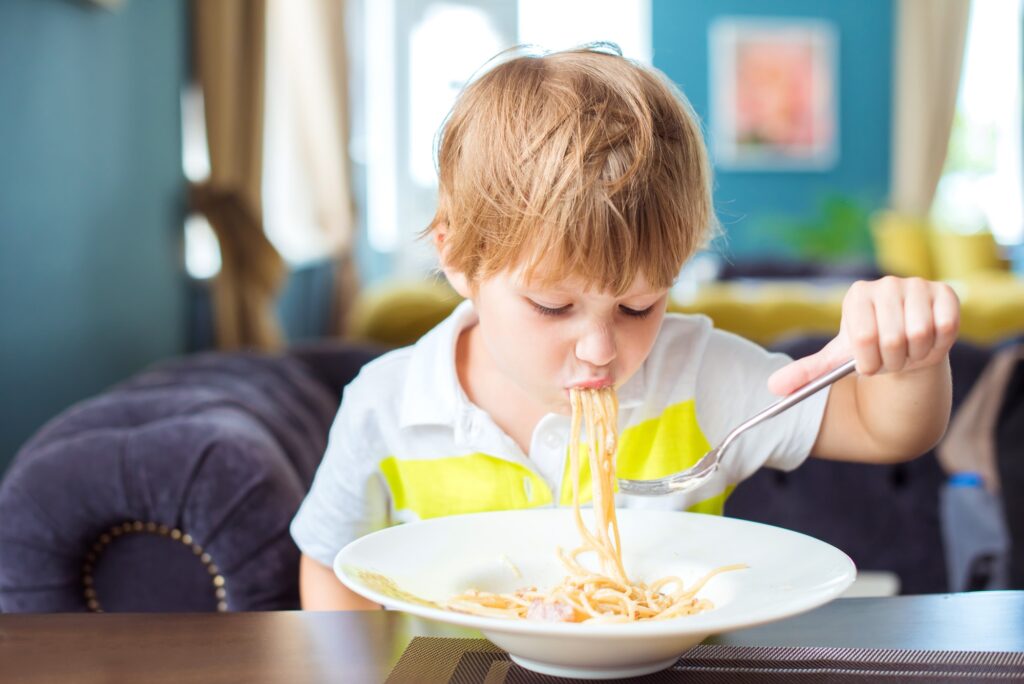 Tasty food, child boy eating spaghetti in the restaurant